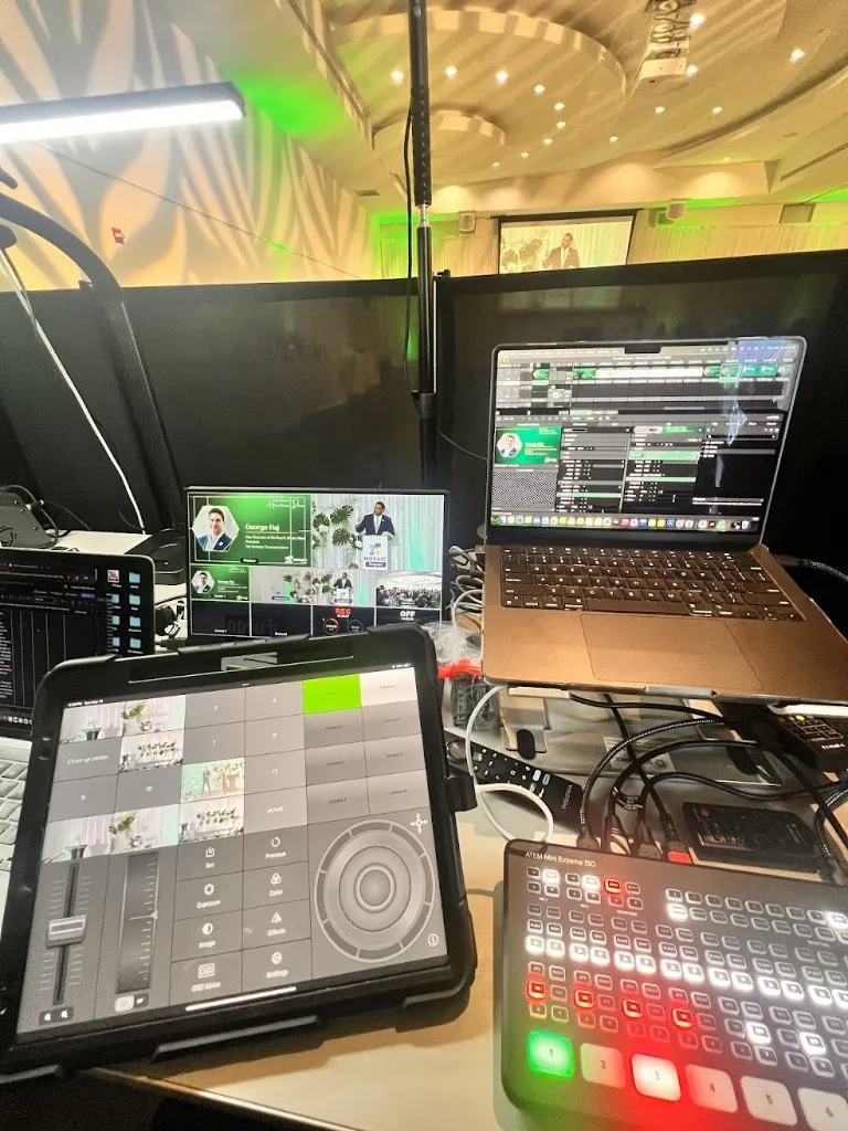 Solfilms live production desk with an ATEM switcher, camera multiview, presentation graphics, and the event stage in the background