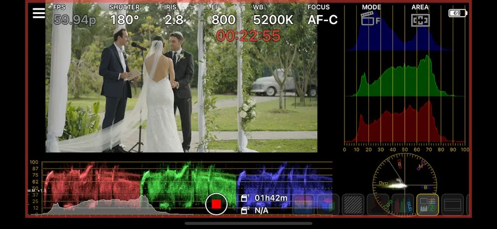 Camera monitor showing outdoor wedding ceremony under a floral arch with RGB histogram, waveform parade, vectorscope, and 59.94p recording overlays